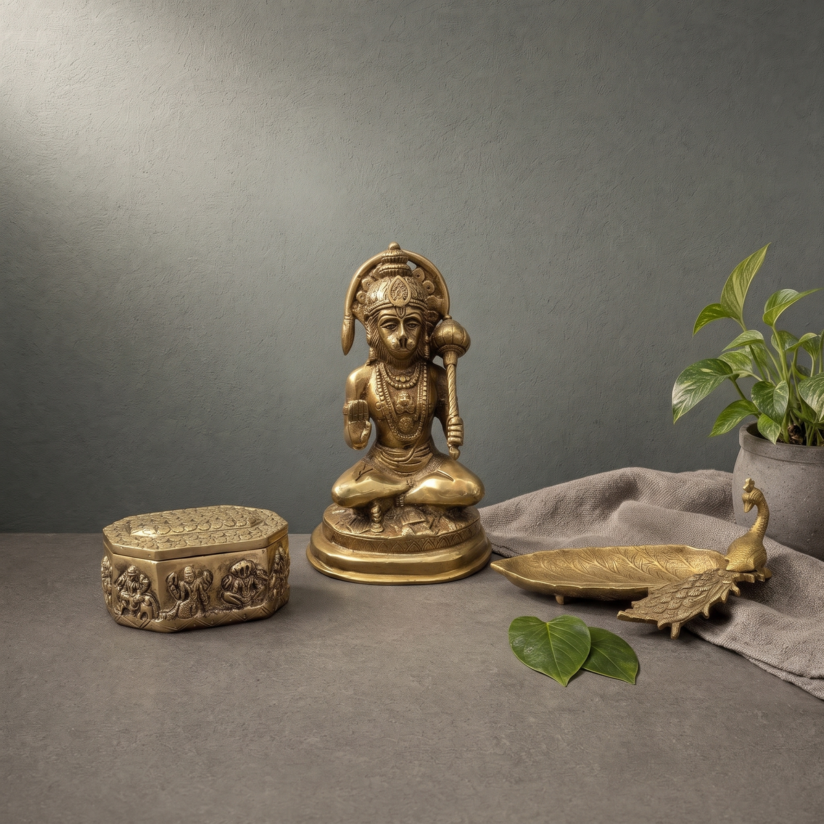 Antique Brass Hanuman Murti with Gada, Antique Brass Peacock Leaf Tray on a stone ledge - Peetal Parampara