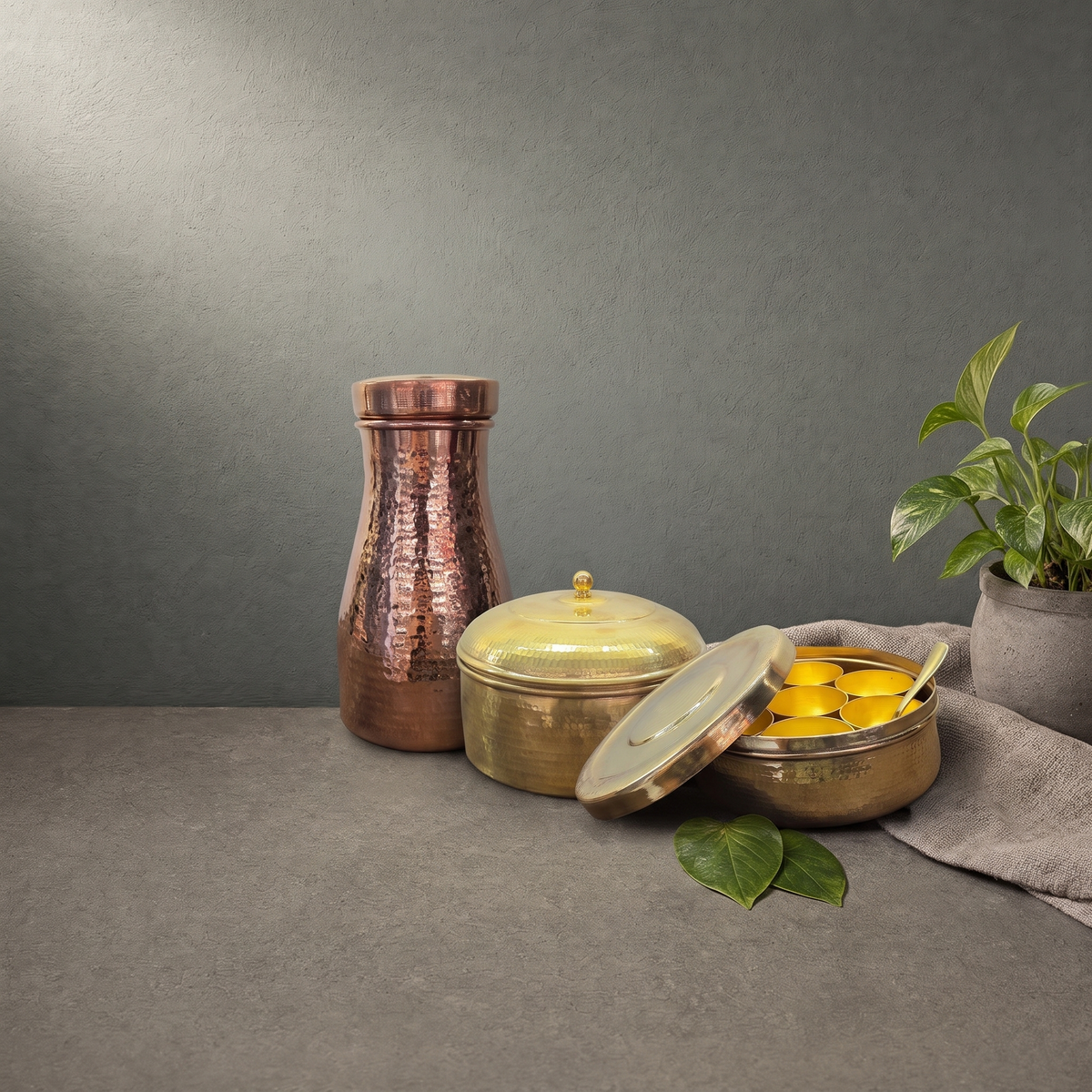 Hand Hammered Brass Masala Dabba, Hand Hammered Brass Roti Box on a stone ledge - Peetal Parampara