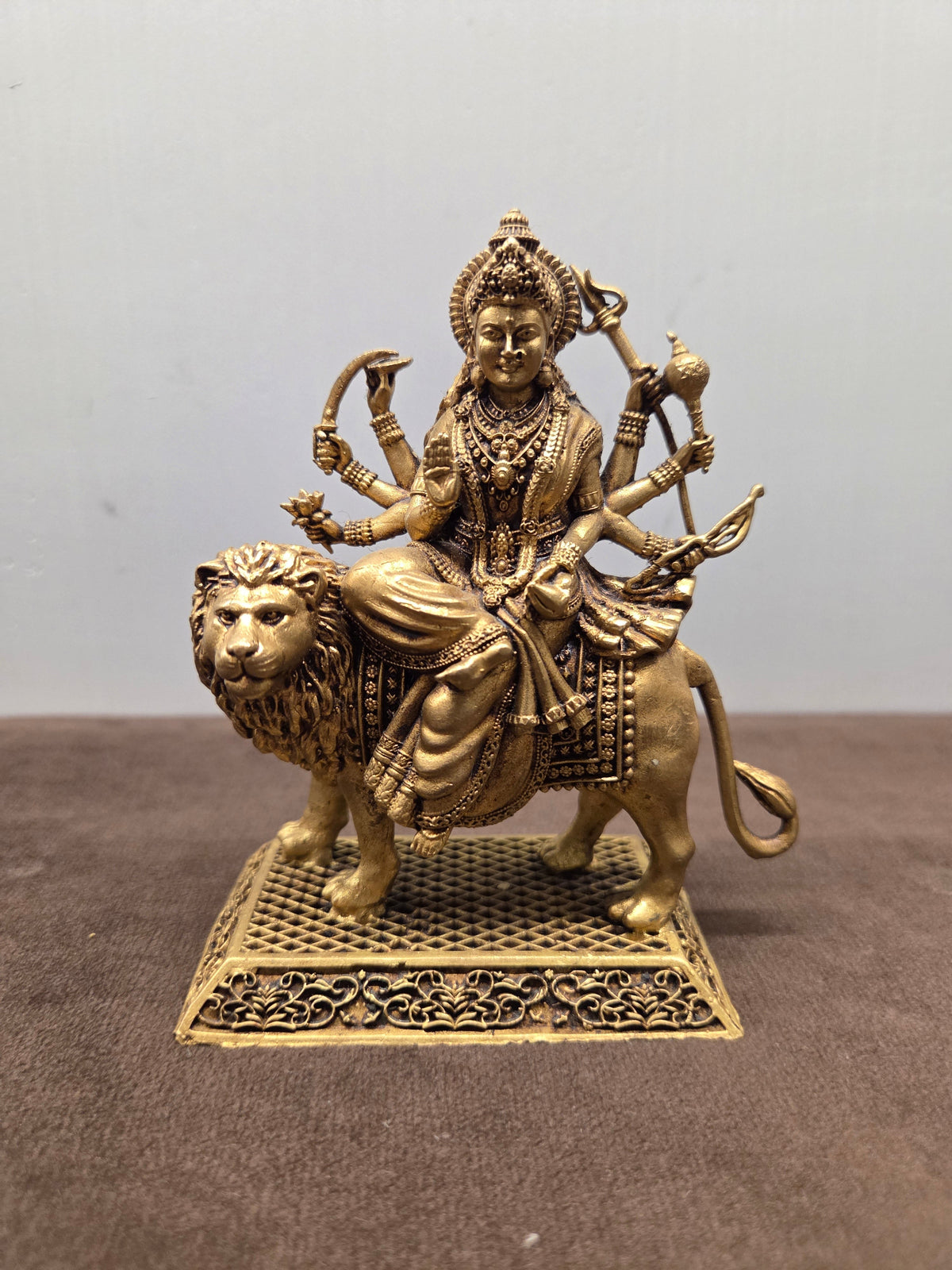 Superfine brass Durga on a standing lion, eight arms, mounted on a pierced jali plinth with a scroll apron - Peetal Parampara