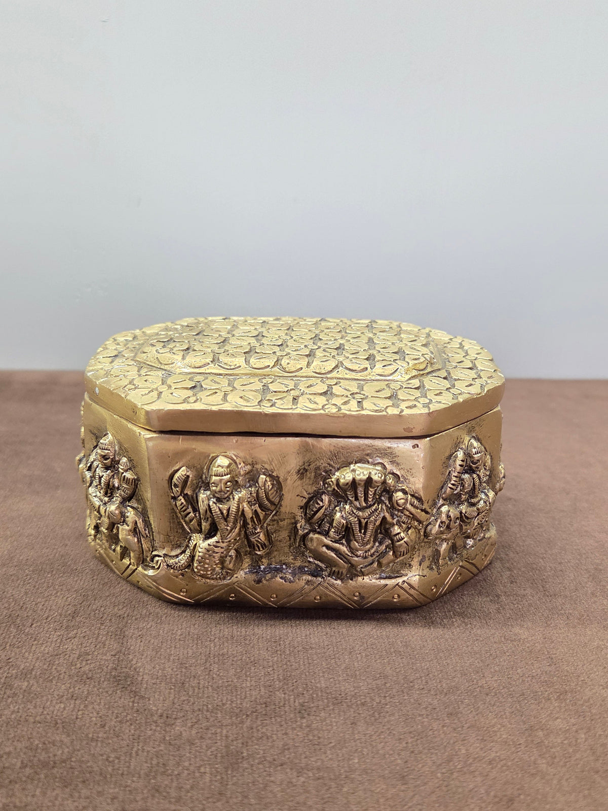 Eight sided brass box with seated figures raised round the wall and a lid of overlapping petals - Peetal Parampara