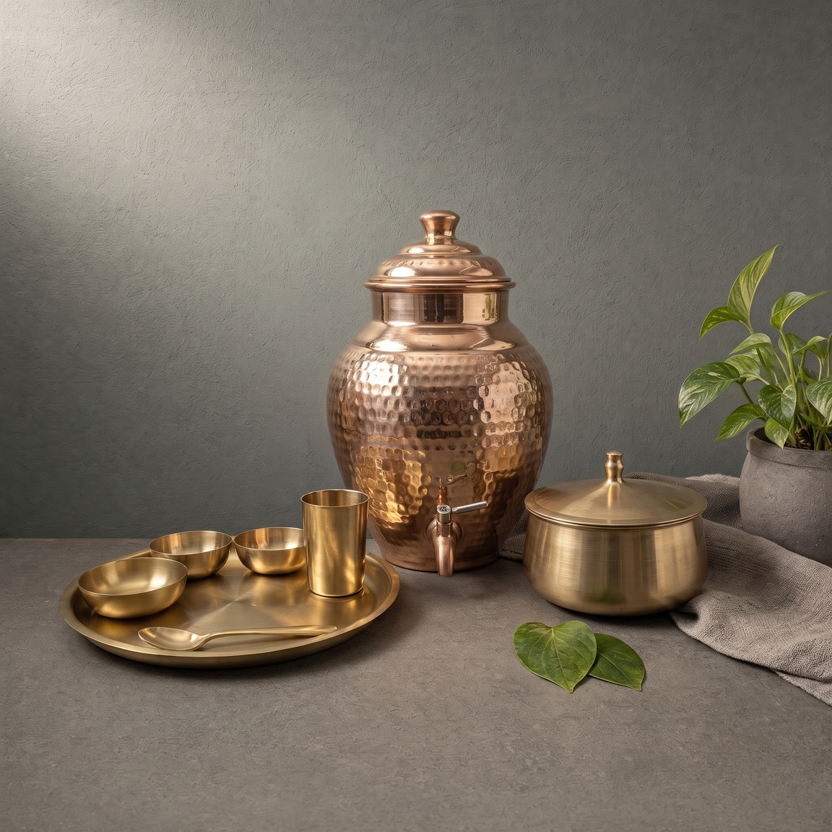 Kansa Thali Set with Deep Well, Hand Hammered Copper Water Dispenser on a stone ledge - Peetal Parampara