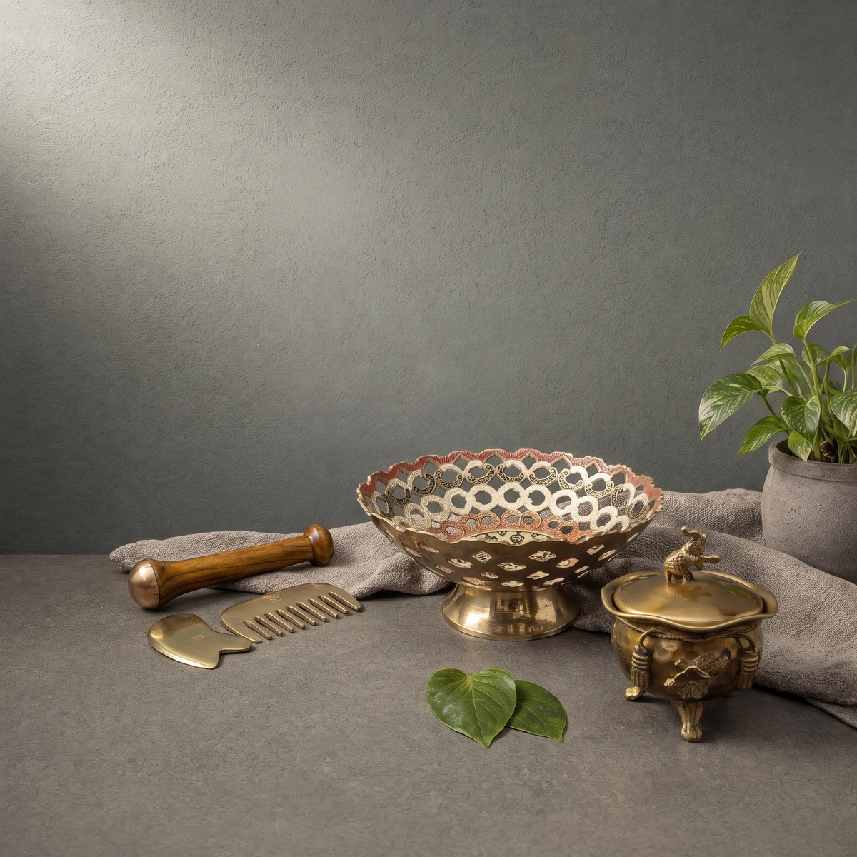 Kansa Massage Wand with Comb, Hand Painted Brass Fruit Bowl on a stone ledge - Peetal Parampara