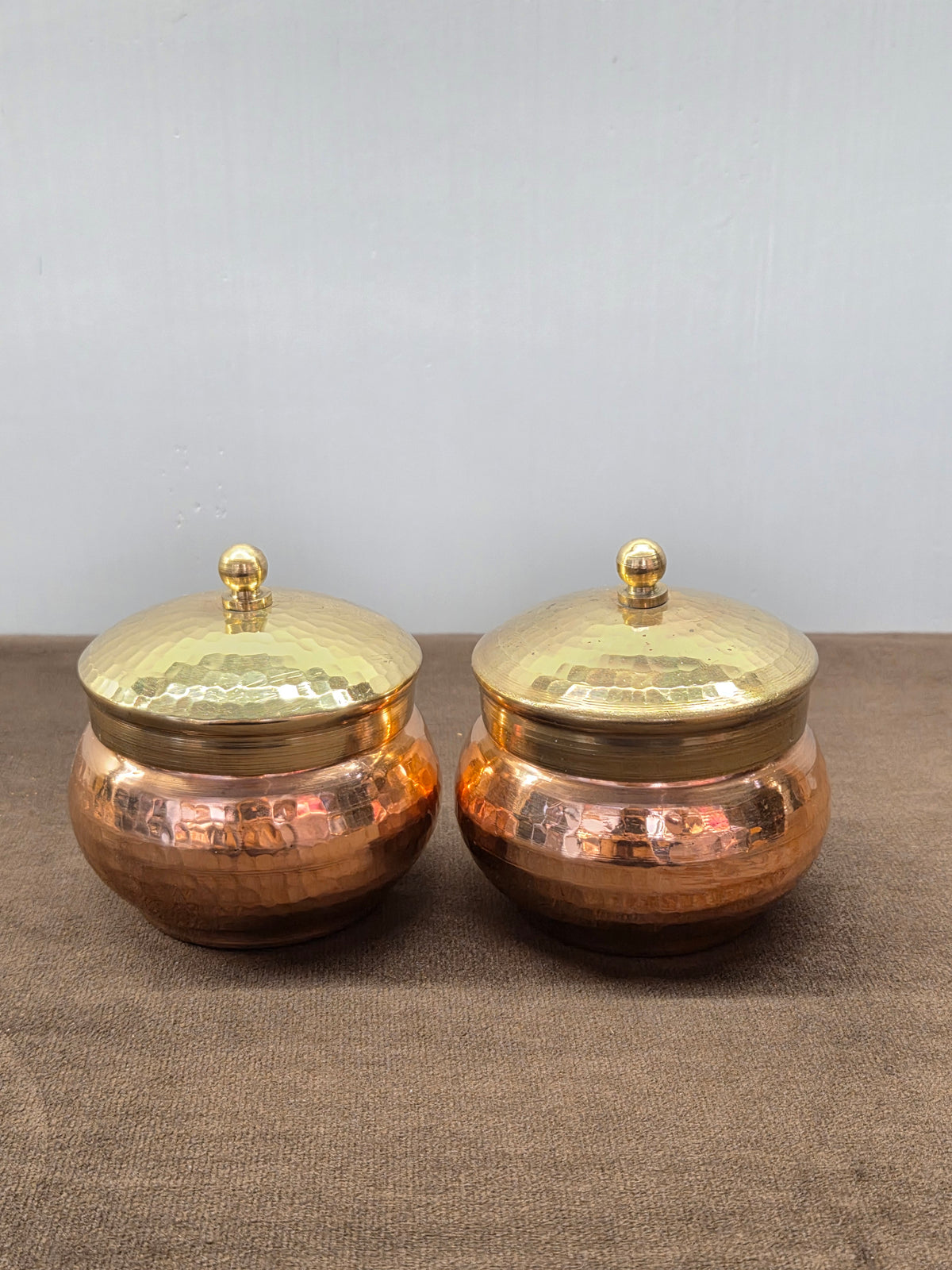 Two hammered copper supari boxes with plain brass collars and domed brass lids topped by ball knobs - Peetal Parampara