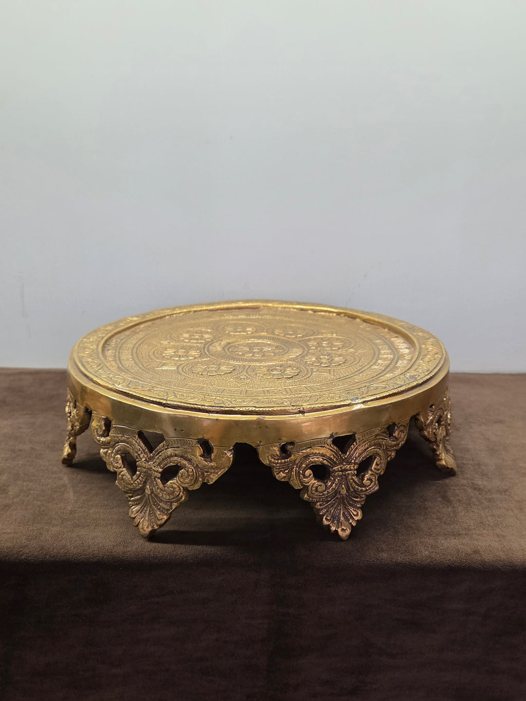 Round brass chowki with an engraved rosette top plate, a pierced apron and cast leaf brackets for feet - Peetal Parampara