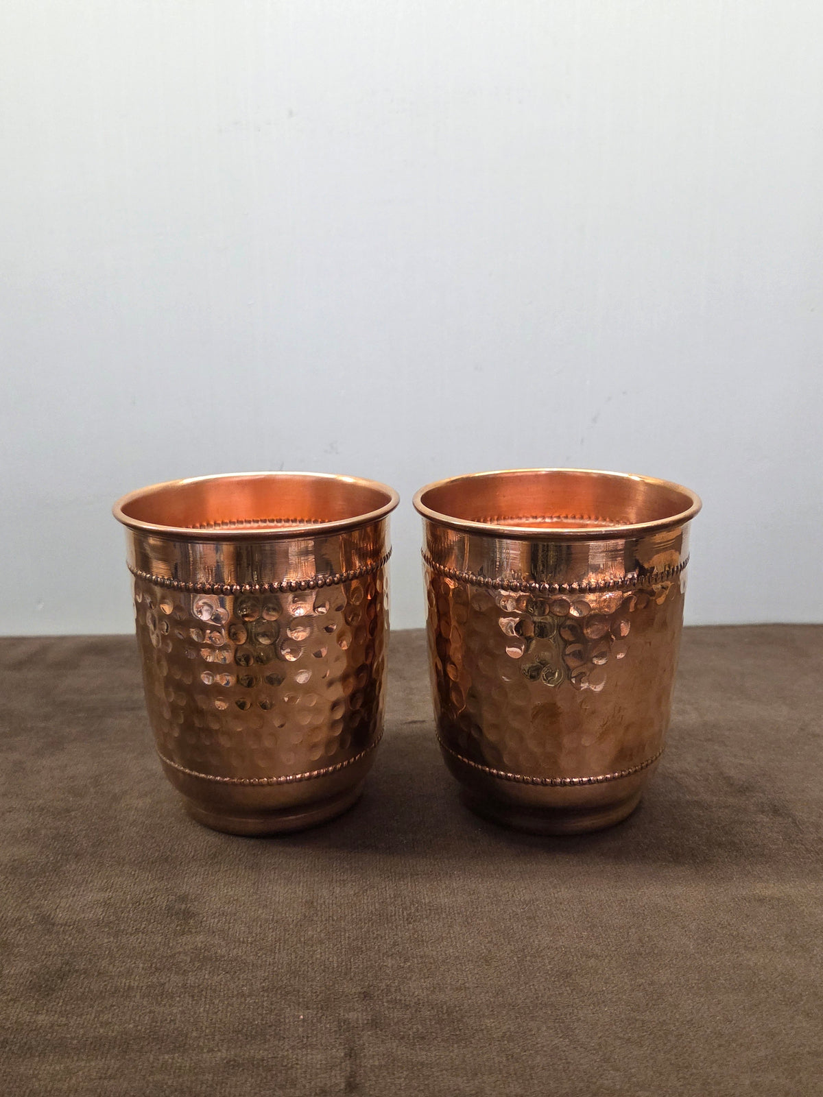 Two straight-sided copper tumblers hammered between rolled beading rows, plain turned-out rims - Peetal Parampara