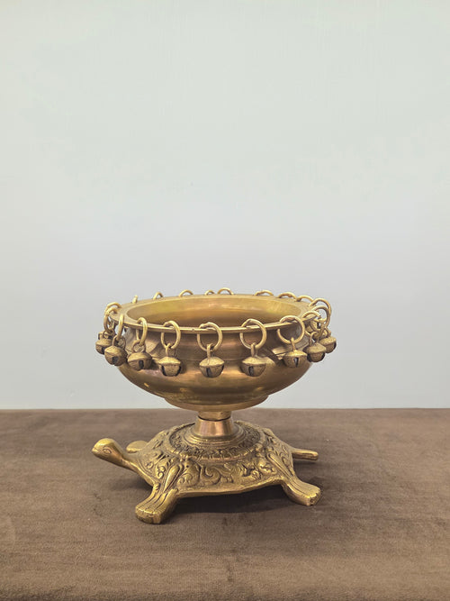 Brass urli on a cast tortoise base, small bells on loose rings right round the rim, antique finish - Peetal Parampara