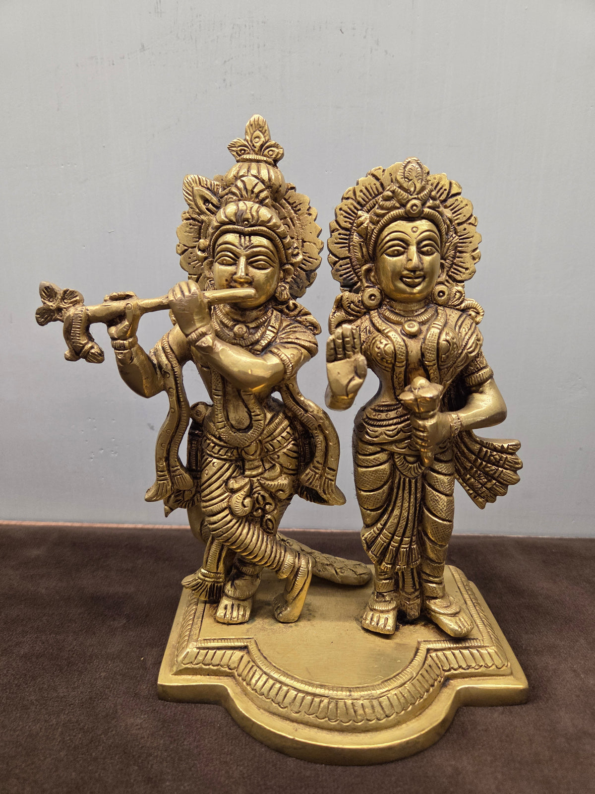 Antique brass Radha Krishna murti on a lobed plinth, leaf-cut crowns behind both heads, flute raised - Peetal Parampara
