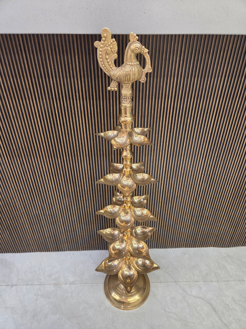 Polished brass layered diya with five tiers of pointed oil cups on a turned stem under a cast peacock - Peetal Parampara