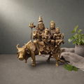 Antique Brass Shiv Parivar Murti on Nandi on a stone ledge against a grey plaster wall - Peetal Parampara