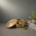 Brass Supari Box with Seven Inner Cups on a stone ledge against a grey plaster wall - Peetal Parampara