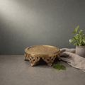 Hand Engraved Brass Chowki on a stone ledge against a grey plaster wall - Peetal Parampara