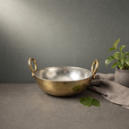 Hand Hammered Brass Kadhai with Kalai Lining on a stone ledge against a grey plaster wall - Peetal Parampara